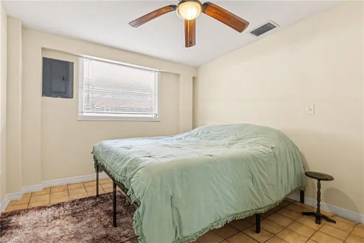 Bedroom featuring electric panel, ceiling fan, and light tile patterned flooring