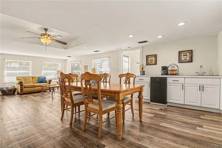 Dining space featuring wood-style finished floors, healthy amount of natural light, a raised ceiling, a ceiling fan, and recessed lighting