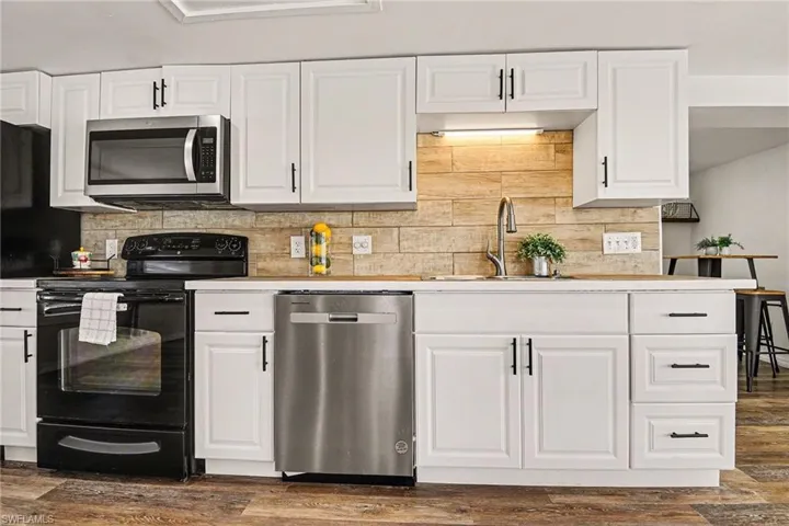 Kitchen with white cabinetry, stainless steel appliances, tasteful backsplash, and wood-style flooring