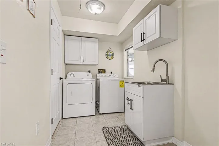 Washroom featuring cabinet space, washing machine and dryer, and light tile patterned floors