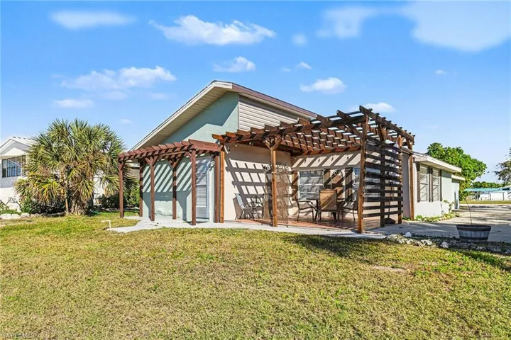 Rear view of house with a pergola, a lawn, and stucco siding