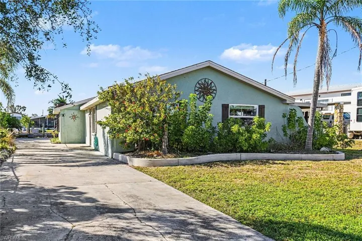 View of front facade with stucco siding, a front lawn, driveway, and a garage