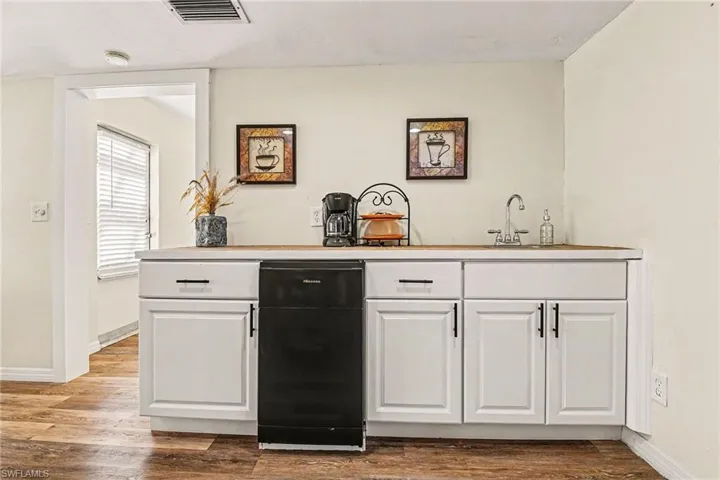Bar with white cabinets, light countertops, and wood finished floors