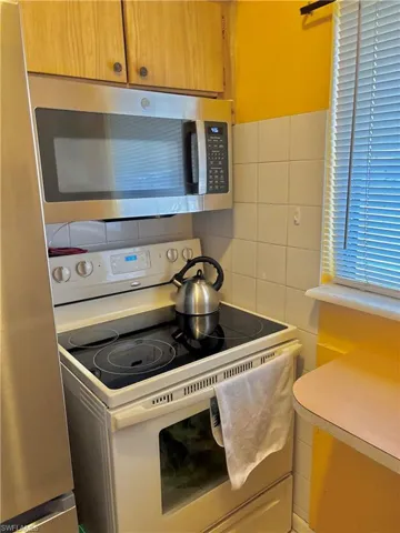 Kitchen with light countertops, appliances with stainless steel finishes, and tile walls