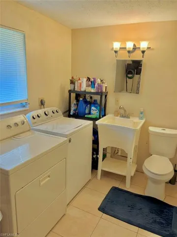 Clothes washing area featuring light tile patterned floors, laundry area, separate washer and dryer, and a textured ceiling