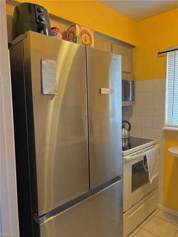 Kitchen with brown cabinets, light tile patterned floors, and stainless steel appliances