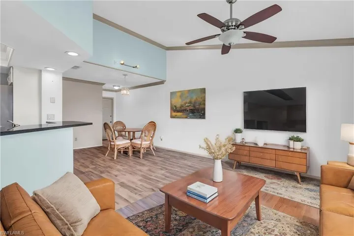 Living room featuring ceiling fan, crown molding, and light hardwood / wood-style flooring