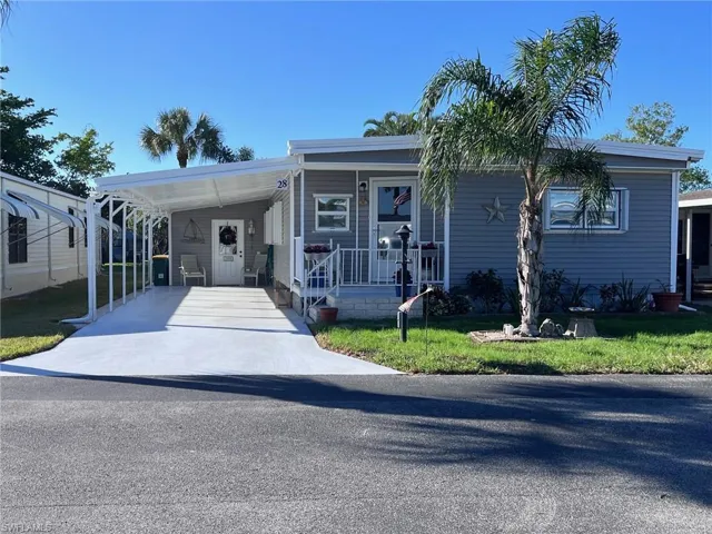 Manufactured / mobile home with a front lawn and a carport