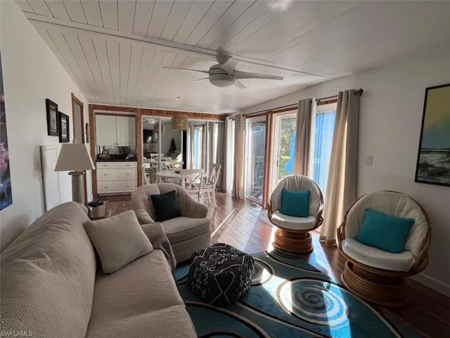 Living room with ceiling fan, light wood-type flooring, and wooden ceiling