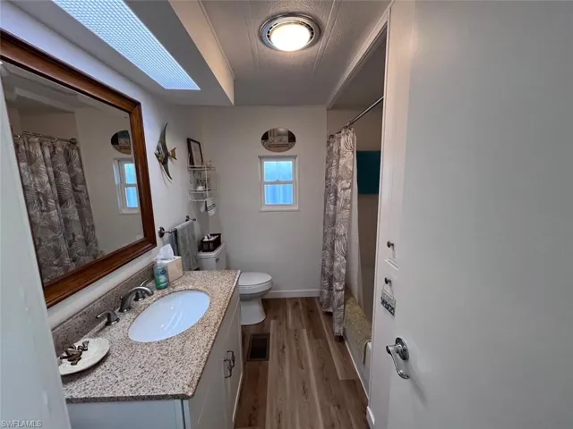 Full Second bathroom with hardwood / wood-style floors, vanity, toilet, and shower / bathtub combination with curtain