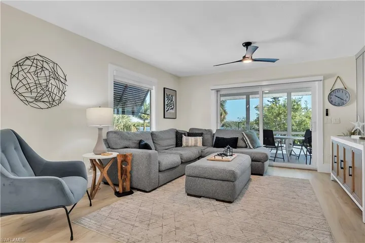 Living area featuring wood-finish flooring, a sleek modern ceiling fan, sliding glass doors, and built-in cabinetry