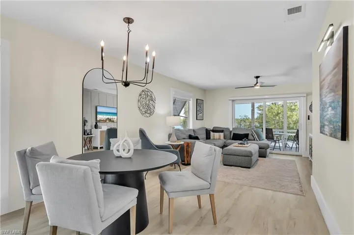 Open-concept room featuring light wood-finish flooring, a multi-arm metal chandelier, and a ceiling fan