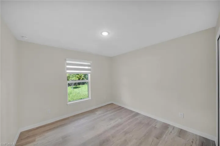Recessed lighting, wood-finish flooring, and a window with blinds