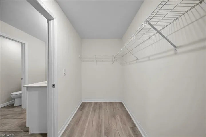 Walk-in closet with wire shelving system and wood-finish flooring