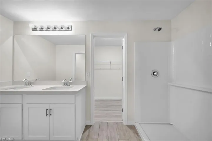 Dual vanity with integrated sinks, white cabinetry, and a full-width mirror