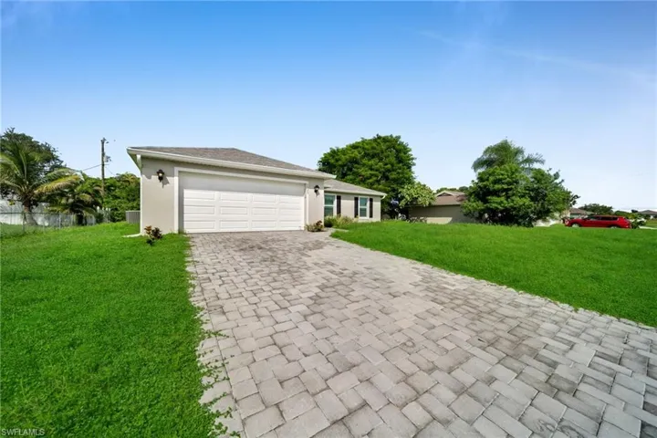 Stucco exterior with a two-car garage, paver driveway, and a shingle roof