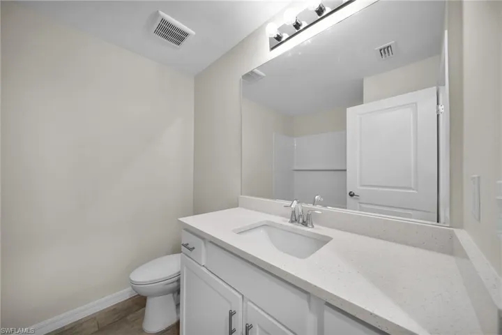 White vanity with a built-in sink, chrome faucet, and light-toned countertop