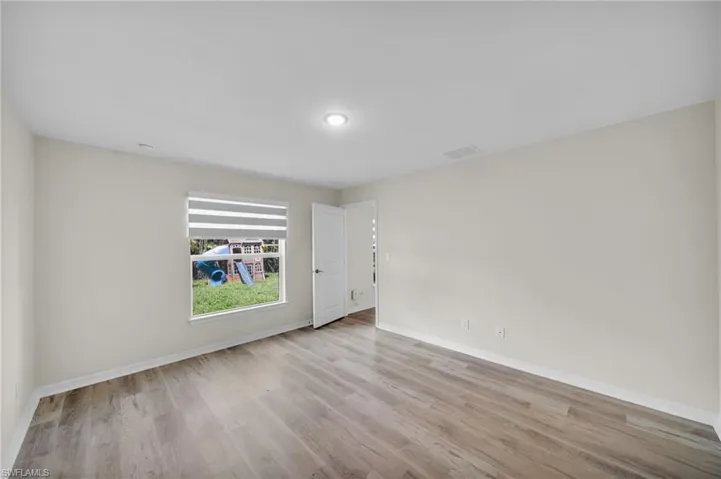 Recessed lighting, wood-finish flooring, white walls, and a window with blinds