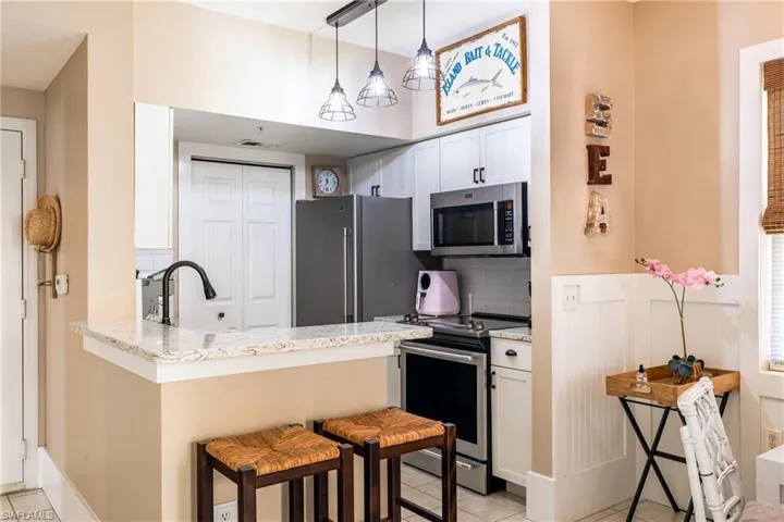 Kitchen featuring stainless steel appliances, white cabinetry, a kitchen breakfast bar, a peninsula, and decorative backsplash