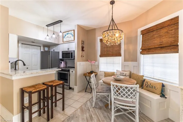 Dining area with a wainscoted wall, light wood-style floors, a decorative wall, breakfast area, and hanging lights