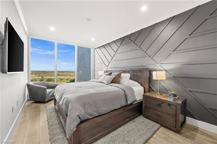 Bedroom featuring light wood-style flooring, a decorative wall, and recessed lighting