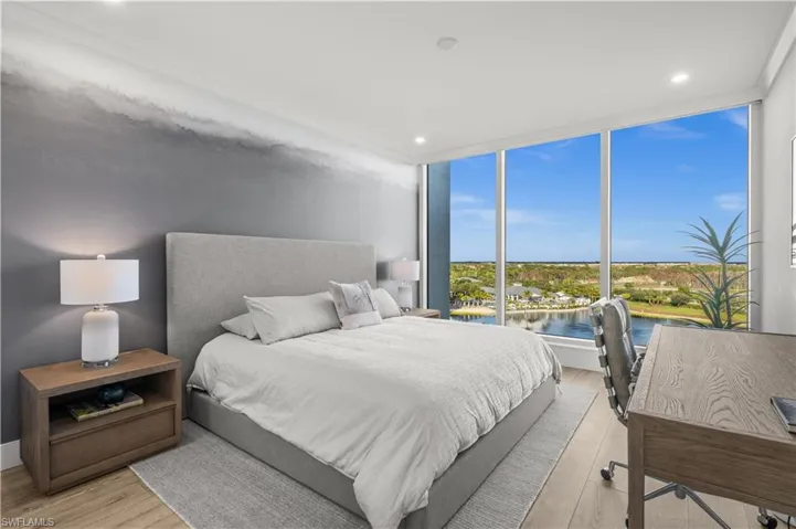 Bedroom with expansive windows, a water view, light wood-style floors, and recessed lighting