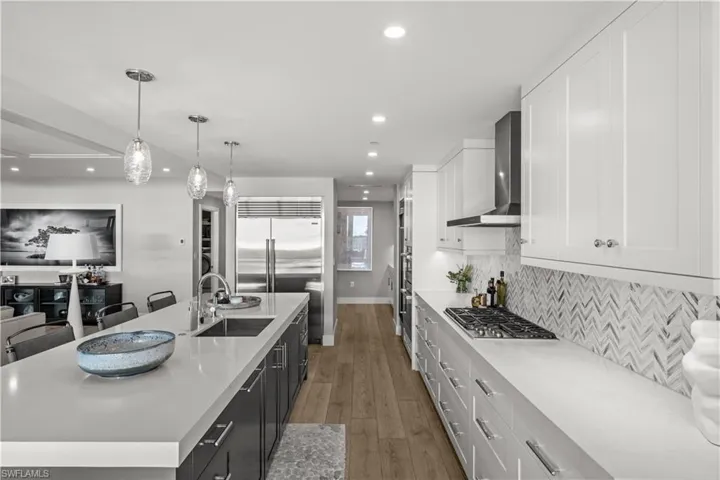 Two tone kitchen featuring two tone cabinets, hanging light fixtures, light wood finished floors, a large island, and stainless steel appliances
