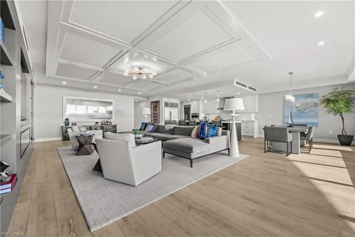Living room with suspended lighting, light wood-type flooring, and coffered ceiling
