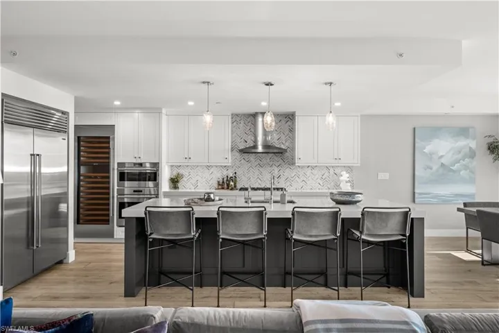 Two tone kitchen featuring dual tone cabinets, a breakfast bar area, light wood-type flooring, stainless steel appliances, and wine cooler