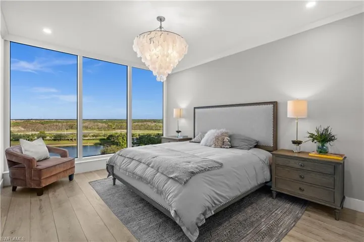 Bedroom with a water view, light wood-type flooring, hanging lights, and crown molding