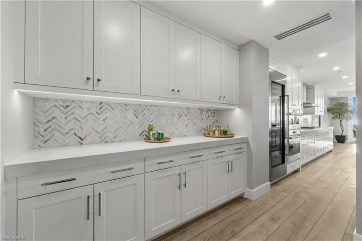 Bar featuring white cabinetry, light wood finished floors, recessed lighting, light stone countertops, and stainless steel appliances