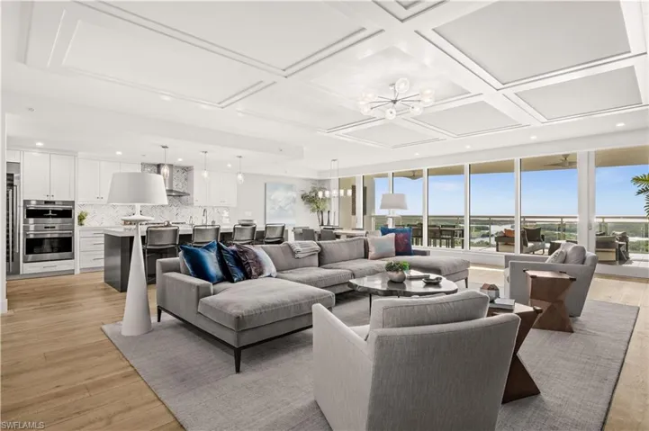 Living area with suspended lighting, coffered ceiling, and light wood-type flooring