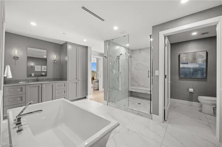 Bathroom with vanity, a marble finish shower, recessed lighting, a freestanding tub, and light marble finish floors
