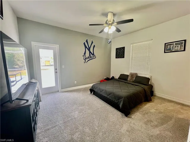 Guest bedroom with baseboards, ceiling fan, and access to it's own private bath and the exterior pool area.
