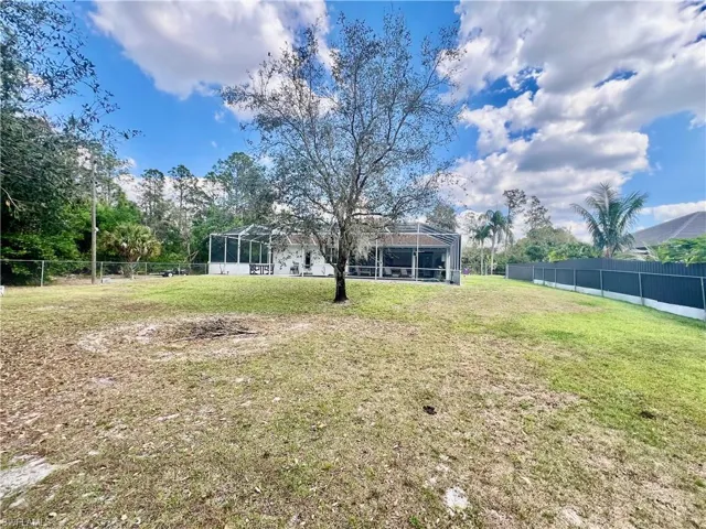 Fenced HALF ACRE lot with shade trees.