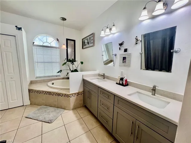 Primary bathroom with double vanity, a garden tub, a sink, separate shower and tile patterned floors