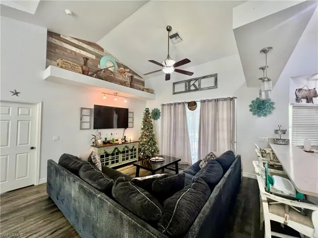 Living room high vaulted ceiling, plant shelves, wood finished floors, and baseboards
