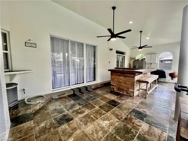 Covered lanai with slate tile and dry bar.
