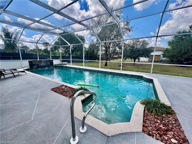 In ground pool with waterfall and a spacious patio