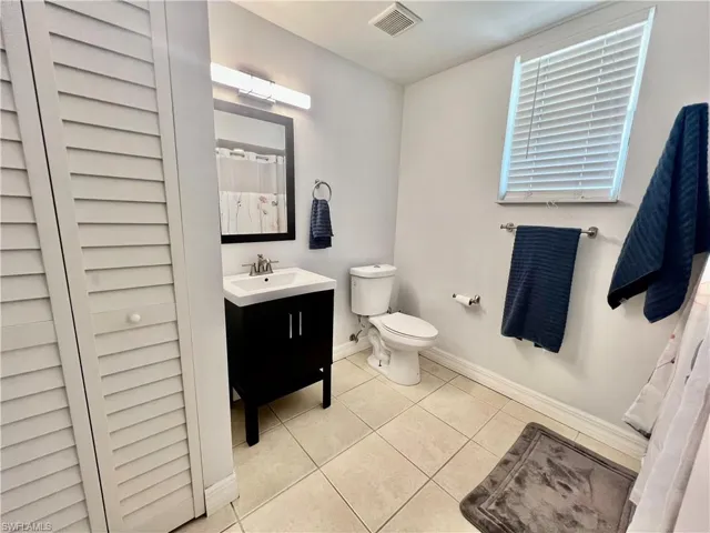 Full bathroom featuring toilet, vanity, baseboards,  tile patterned floors