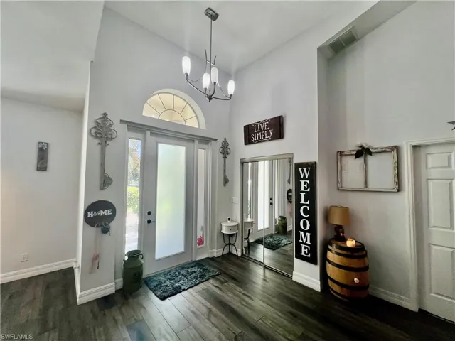 Entrance foyer  with wood-type flooring, an inviting chandelier, and a high ceiling