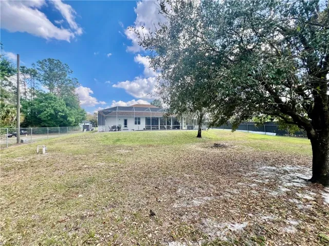 Fenced HALF ACRE lot with shade trees.