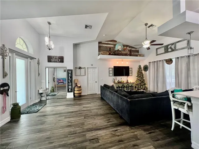Living room featuring high vaulted ceiling, visible vents, and wood-style flooring
