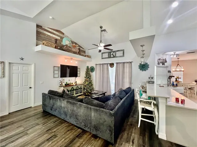 Living room high vaulted ceiling, plant shelves, wood finished floors, and baseboards