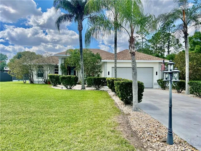 Single story home featuring extra long driveway lined with palm trees.