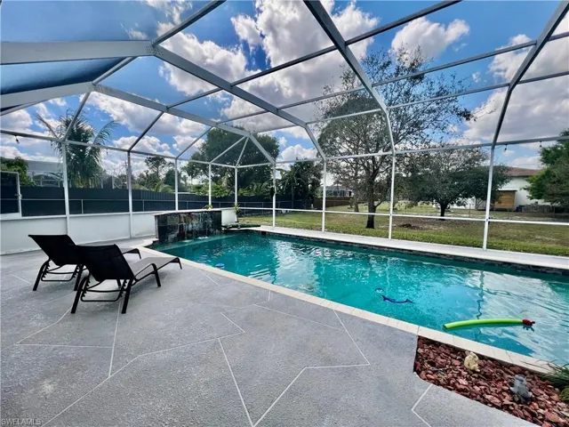 In ground pool with waterfall and a spacious patio