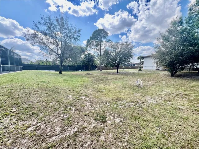 Fenced HALF ACRE lot with shade trees.