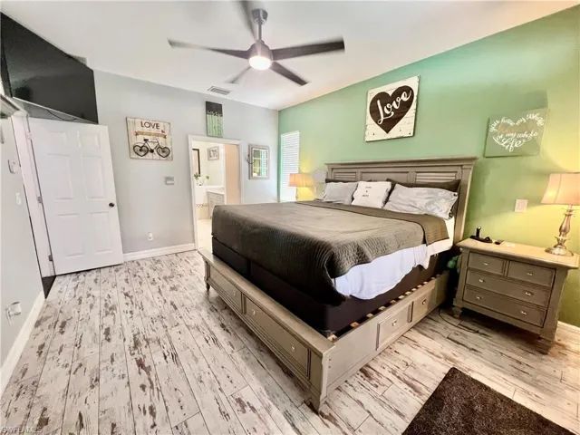 Bedroom with visible vents, light wood-style flooring, ensuite bathroom, ceiling fan, and baseboards