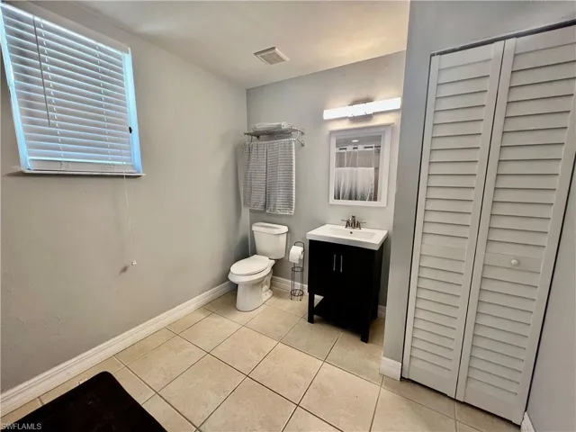 Bathroom with tile patterned flooring, toilet, vanity, and baseboards