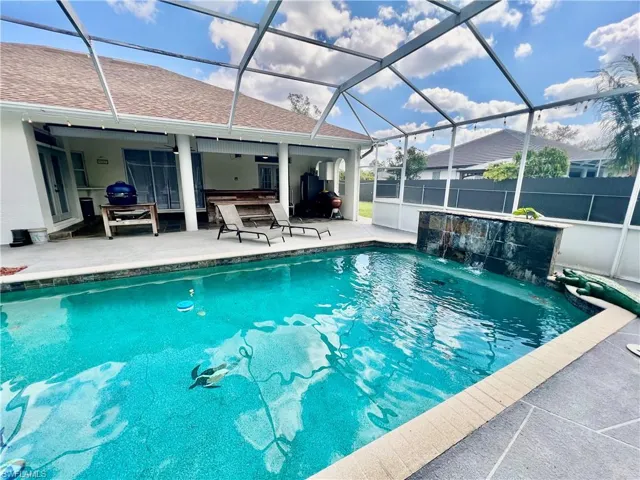 In ground pool with waterfall and a spacious patio